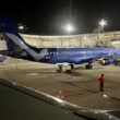 a blue airplane on a tarmac at night