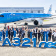 a group of people standing in front of a large blue airplane