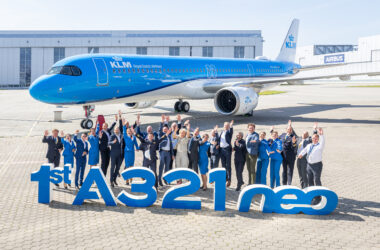 a group of people standing in front of a large blue airplane