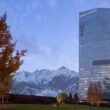 a tall building with trees and mountains in the background