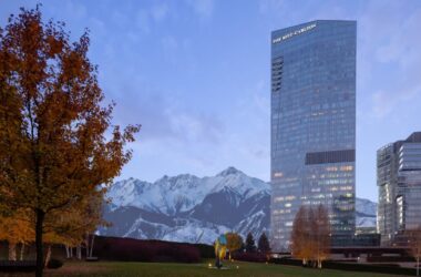 a tall building with trees and mountains in the background