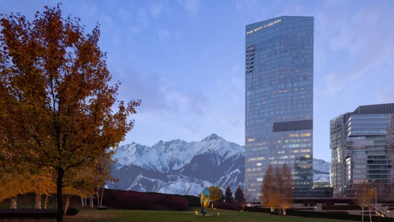 a tall building with trees and mountains in the background