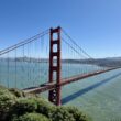 Golden Gate Bridge over water with trees and a city in the background