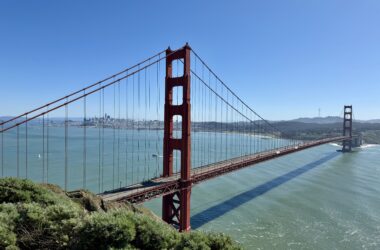 Golden Gate Bridge over water with trees and a city in the background