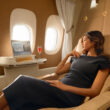 a woman in a black dress sitting in a chair in a plane