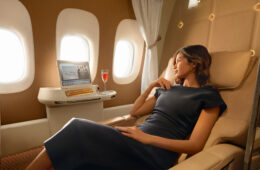a woman in a black dress sitting in a chair in a plane
