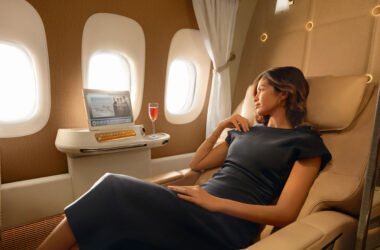 a woman in a black dress sitting in a chair in a plane