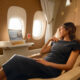 a woman in a black dress sitting in a chair in a plane