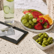 a plate of fruit and a glass of water next to a drink
