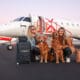 a group of women with dogs and luggage in front of an airplane